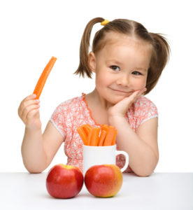 Cute little girl eats carrot and apples